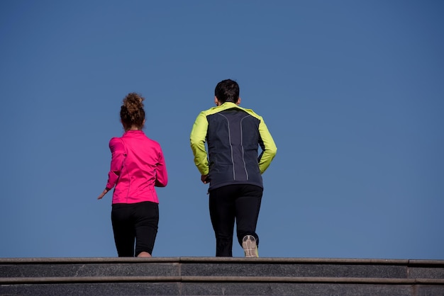 jeune couple en bonne santé faisant du jogging sur les marches tôt le matin