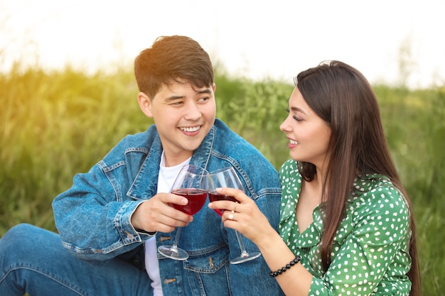 Jeune couple buvant du vin en pique-nique dans le parc