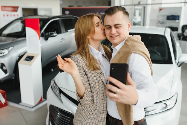 Jeune couple byuing une voiture dans une salle d'exposition de voiture