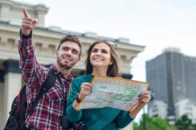 Jeune couple avec une carte de la ville. Heureux touristes visitant la ville avec carte