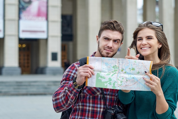 Jeune couple avec une carte de la ville. Heureux touristes visitant la ville avec carte