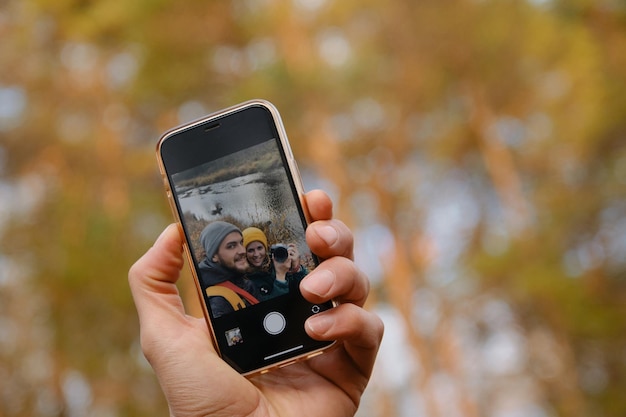 Un jeune couple caucasien amoureux prend un selfie sur un smartphone lors d'une randonnée dans la nature