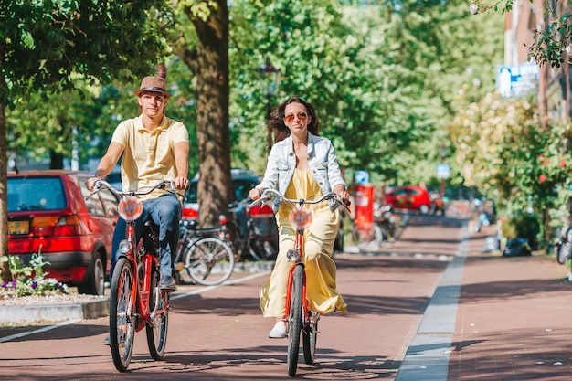 Jeune couple caucasien heureux sur des vélos dans les vieilles rues d'Amsterdam