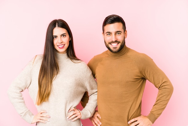 Jeune couple caucasien isolé confiant en gardant les mains sur les hanches.