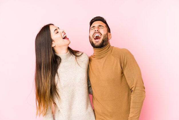 Jeune couple caucasien isolé détendu et heureux rire, cou tendu montrant les dents.