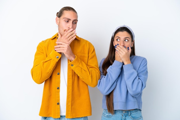 Jeune couple caucasien isolé sur fond blanc couvrant la bouche avec les mains