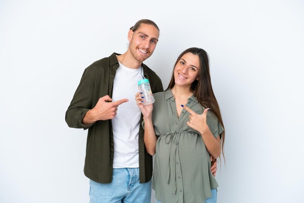Jeune couple caucasien isolé sur fond blanc enceinte et tenant un biberon