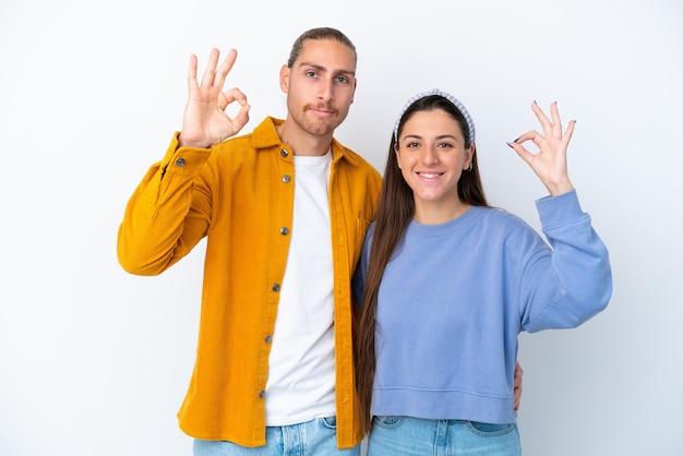 Jeune couple caucasien isolé sur fond blanc montrant un signe ok avec les doigts