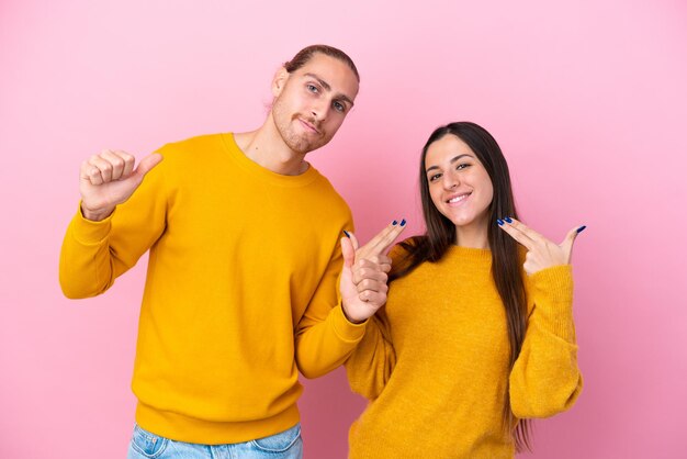 Jeune couple caucasien isolé sur fond rose fier et satisfait de vous-même concept d'amour