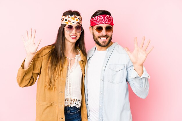 Jeune couple caucasien portant un festival de musique vêtements isolés souriant joyeux montrant le numéro cinq avec les doigts.