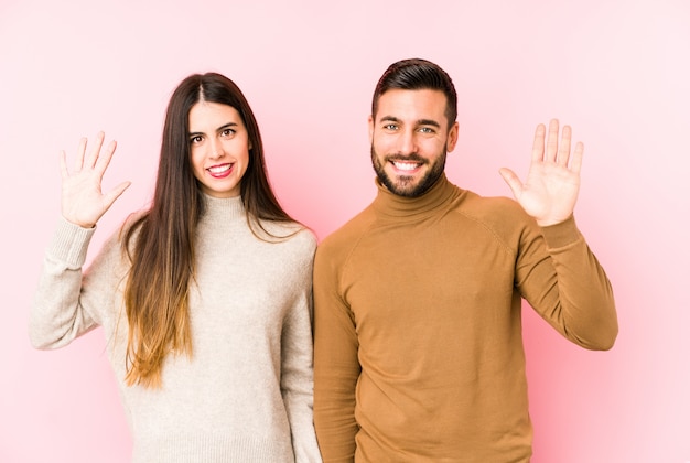 Jeune couple caucasien souriant joyeux montrant le numéro cinq avec les doigts.