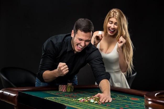 Jeune couple célébrant la victoire à la table de roulette au casino