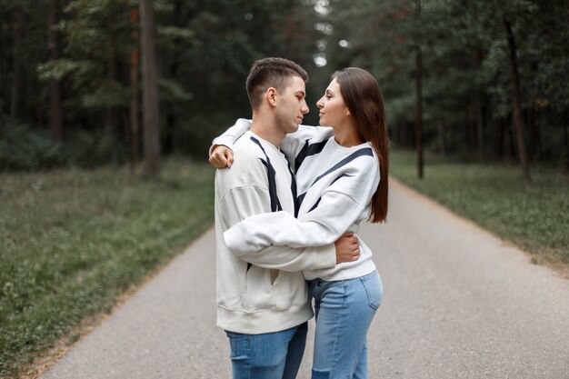 Jeune couple en chandails blancs à la mode serrant dans le parc