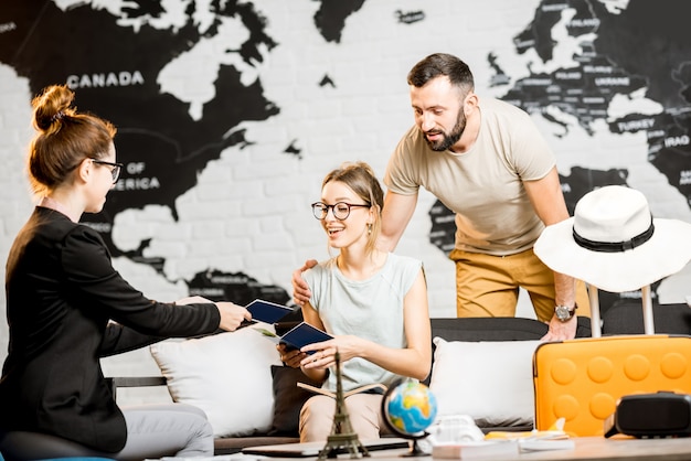 Photo jeune couple charmant assis avec le directeur au bureau de l'agence de voyages se préparant pour des vacances d'été