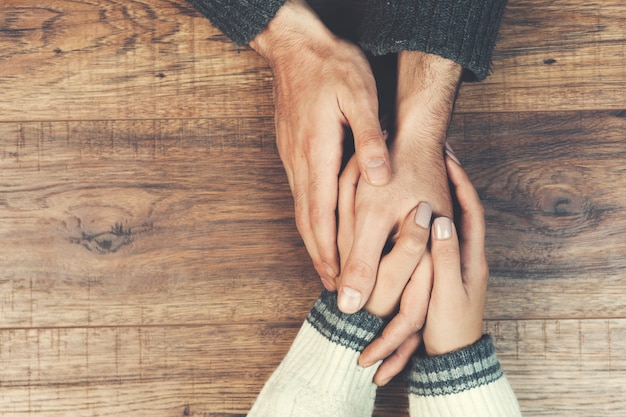 Jeune couple charmant mains sur table