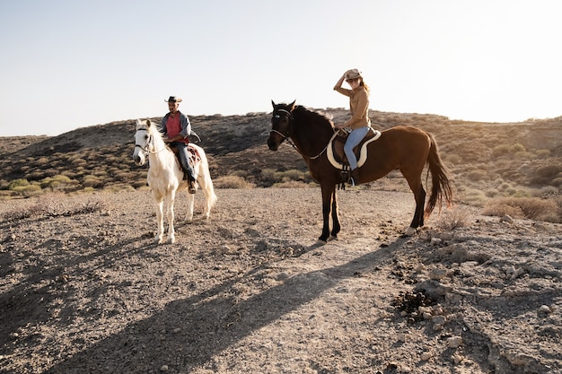 Jeune couple à cheval faisant une excursion à la campagne pendant l'heure du coucher du soleil - L'accent est mis sur le visage de la femme