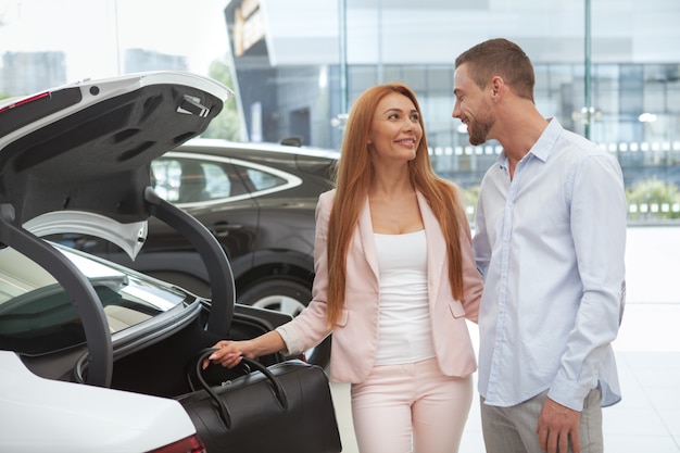 Jeune couple chic achetant une voiture de luxe chez le concessionnaire