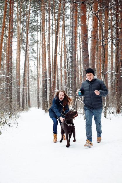 Jeune couple avec un chien s'amusant en hiver