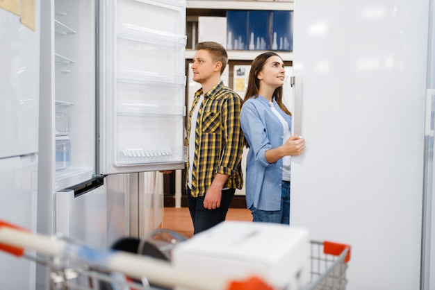 Jeune couple choisissant un réfrigérateur en magasin