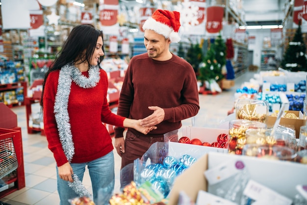 Jeune couple choisit des jouets d'arbre de Noël en boutique