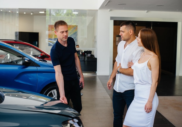 Un Jeune Couple Choisit Une Nouvelle Voiture Chez Le Concessionnaire Et Consulte Un Représentant De La Concession. Voitures D'occasion à Vendre. Réalisation De Rêve.