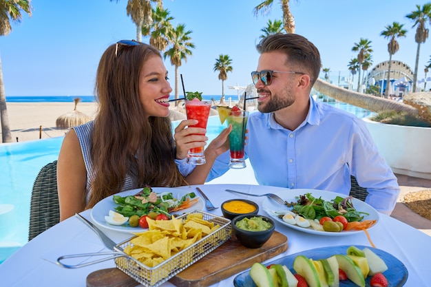 Jeune couple avec cocktails au restaurant de la piscine