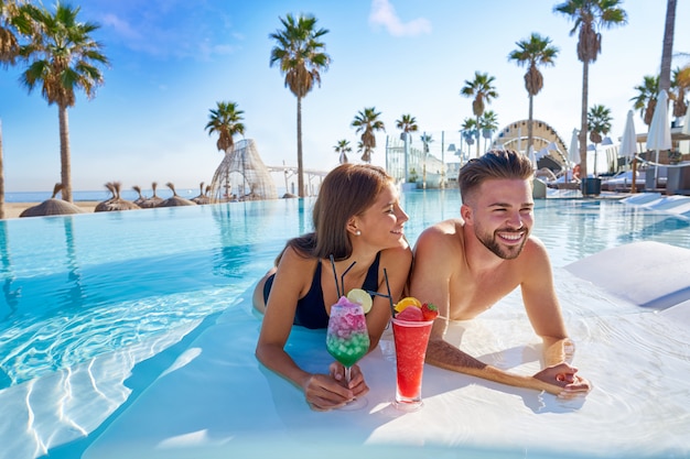 Jeune couple sur les cocktails à la piscine à débordement