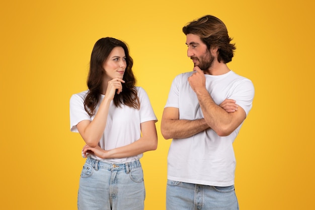 Un jeune couple contemplatif en chemise blanche et en jean se regardant avec réflexion