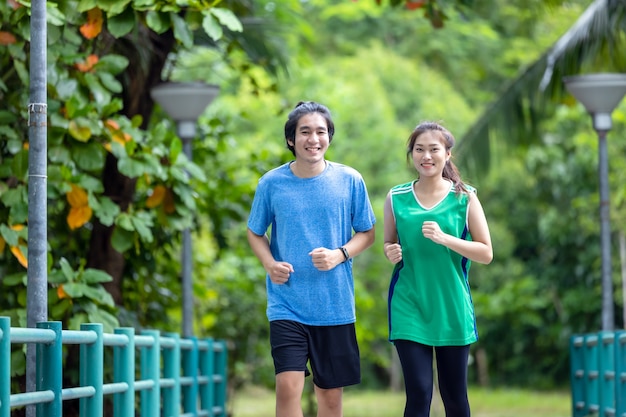 Un jeune couple courant dans le parc, le sport et l'amour sont combinés dans ce concept, avec un homme et une femme sportifs s'entraînant ensemble.