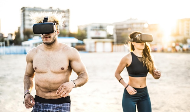 Jeune couple courant à la plage avec casque de lunettes de réalité virtuelle