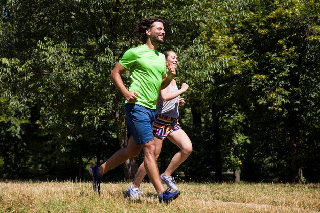 Jeune couple en cours d&#39;exécution dans le parc par une journée ensoleillée