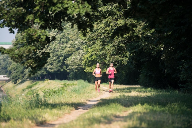 Jeune couple en cours d'exécution dans la zone boisée de la forêt - Entraînement et exercice pour l'endurance du marathon de course à pied - Concept de mode de vie sain de remise en forme