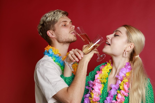 Jeune couple croise les bras et boit du champagne sur fond rouge