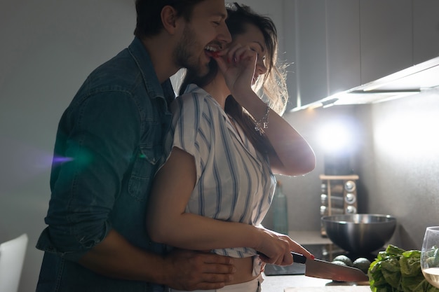 Jeune couple cuisinant un délicieux dîner ensemble dans une cuisine le soir