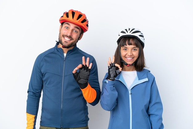 Jeune couple cycliste isolé sur fond blanc montrant un signe ok avec les doigts