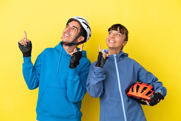 Jeune couple cycliste isolé sur fond jaune pointant avec l'index une excellente idée