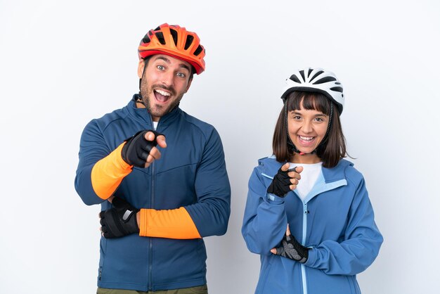 Jeune couple de cyclistes isolé sur fond blanc pointe le doigt vers vous avec une expression confiante