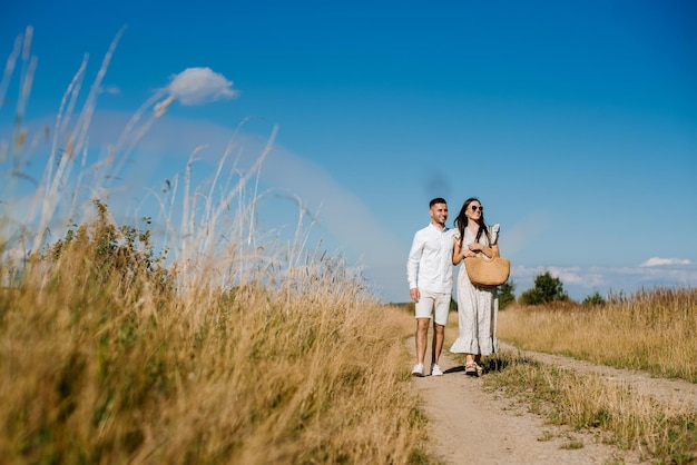 Jeune couple dans le champ de blé aux beaux jours d'été. Un couple amoureux s'amuse dans un champ doré. Couple romantique en vêtements décontractés à l'extérieur sur un terrain sans limites