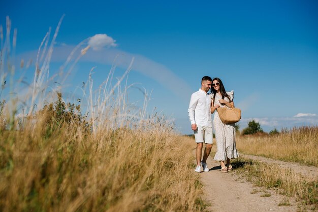 Jeune couple dans le champ de blé aux beaux jours d'été. Un couple amoureux s'amuse dans un champ doré. Couple romantique en vêtements décontractés à l'extérieur sur un terrain sans limites