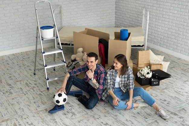 Jeune couple dans une nouvelle maison relaxante sur fond de grosses boîtes. Concept pendaison de crémaillère, a commencé à vivre ensemble.