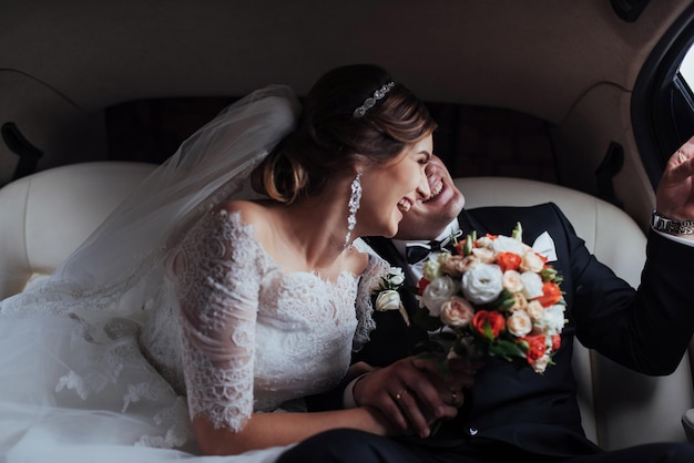 Un jeune couple dans une voiture le jour du mariage.