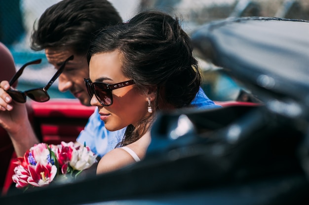 Jeune couple dans des voitures anciennes