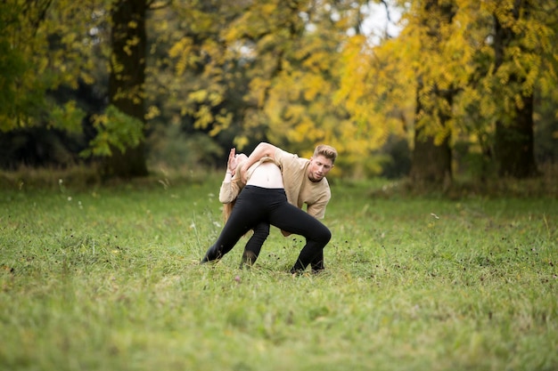 Un jeune couple danse sur un champ herbeux dans un parc.