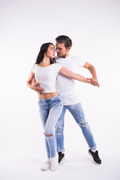 Jeune couple danse danse latine sociale bachata, merengue, salsa. Deux élégance posent sur blanc