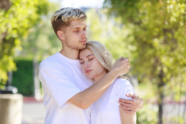 Jeune couple debout au parc et l'homme a étreint sa petite amie Photo de haute qualité