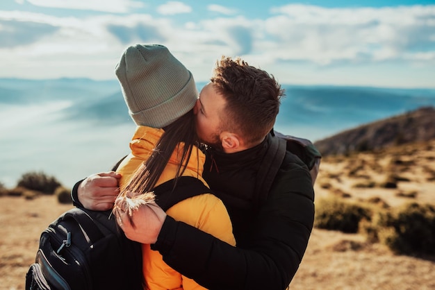 Un jeune couple debout au sommet d'une montagne