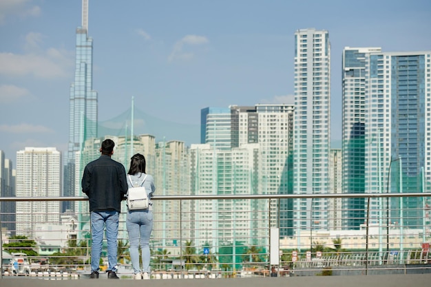 Jeune couple debout sur le pont et profitant de la vue sur la ville depuis l'arrière