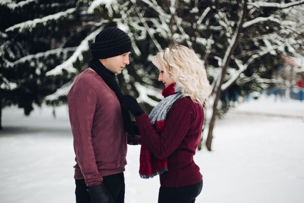 Jeune couple debout et se regardant dans la forêt de neige.