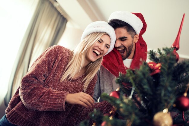 Jeune couple décorant un sapin de Noël