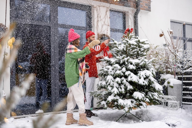 Le jeune couple décore l'arbre de Noël à l'arrière-cour